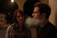 Man smokes cigarette while woman watches